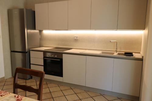 a kitchen with white cabinets and a sink and a stove at Villeriunite - Villa Dalia in Baia Verde