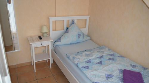 a small bedroom with a bed and a night stand at Hotel Dorfkrug Büsum in Büsum