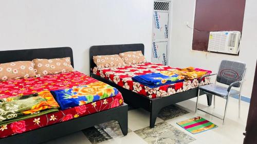 a bedroom with two twin beds and a chair at Shree Sidhi Vinayak Guest House in Gaya