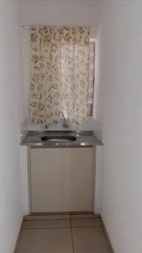 a small bathroom with a window with a sink at Atibaia Flat in Atibaia