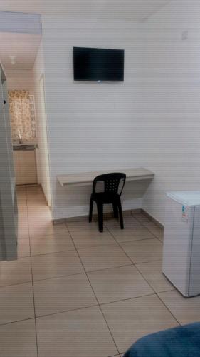 a chair sitting in a room with a tv on the wall at Atibaia Flat in Atibaia