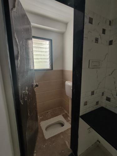 a bathroom with a toilet in the floor and a window at Amrutyog homes in Wai