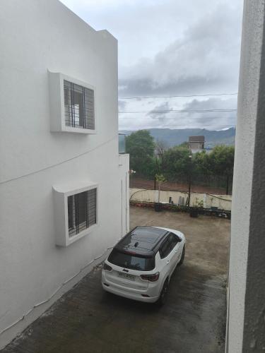 a white car parked in a parking lot next to a building at Amrutyog homes in Wai