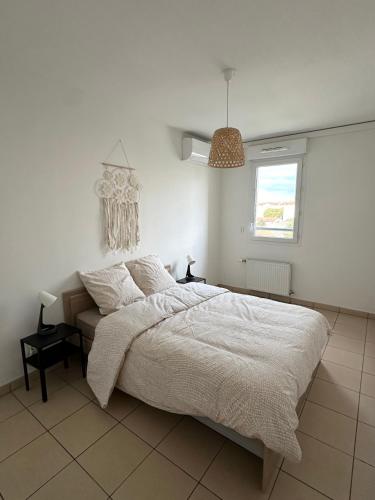 Appartement T3 في فيليوربان: غرفة نوم بيضاء مع سرير ونافذة