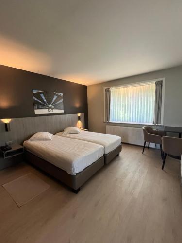 Un dormitorio con una cama, un escritorio y una mesa. en Hotel In den Bonten Os, en Rijmenam