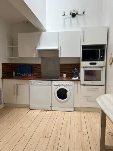 une cuisine avec des armoires blanches et une laveuse et une sécheuse dans l'établissement Le Loft, l'annexe, à Lorient