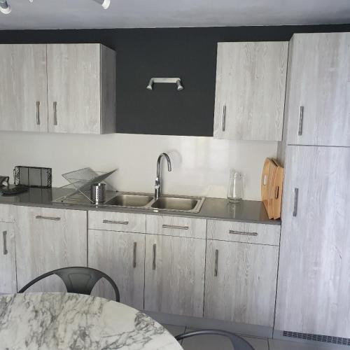 a kitchen with white cabinets and a sink and a table at Domaine Garmidou in Lucq-de-Béarn