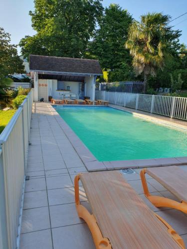 a swimming pool with a wooden bench next to a fence at Domaine Garmidou in Lucq-de-Béarn