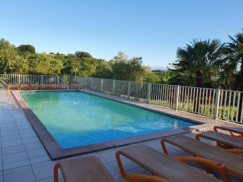 a large swimming pool with benches and a fence at Domaine Garmidou in Lucq-de-Béarn