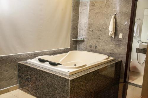y baño con bañera y espejo. en San Lucas Hotel - 06km de Maringa, en Sarandi