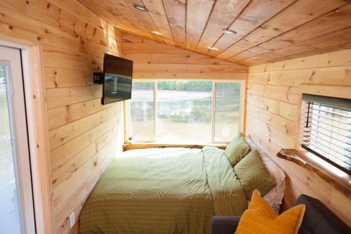 1 dormitorio en una cabaña de madera con 1 cama y TV en Floating Tiny Home #1, en Vermilion