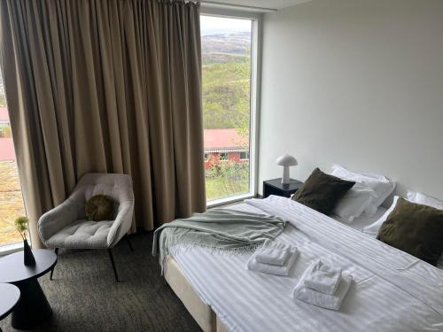 a bedroom with a bed and a chair and a window at Hótel Bifröst in Bifrost