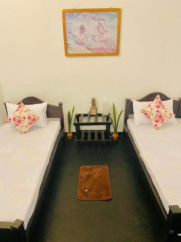 two beds in a room with a table between them at Zensigiri Ayurveda Wellness Homestay in Sigiriya