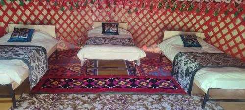 a room with four beds in a red and white tent at Jhibek in Dzhetyoguz