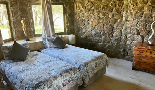 una camera da letto con due letti e un muro di pietra di Sambane Game Lodge a Bracondale