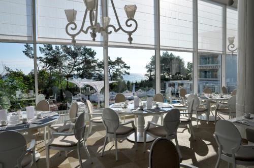 a restaurant with white tables and chairs and large windows at Hotel Bryza Resort & Spa in Jurata