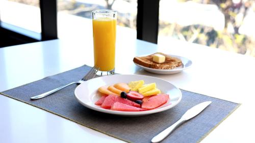 un piatto di frutta su un tavolo con un bicchiere di succo d'arancia di Quartz Care Hotel & Spa Tijuana a Tijuana