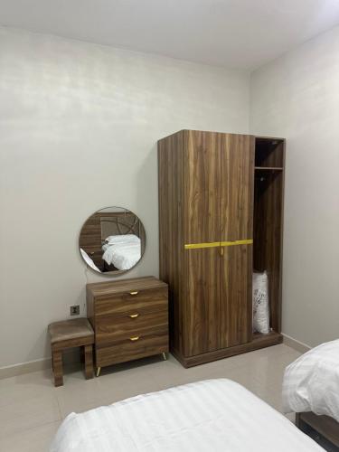 a bedroom with a wooden cabinet and a mirror at نزل جنى 2 in Dammam