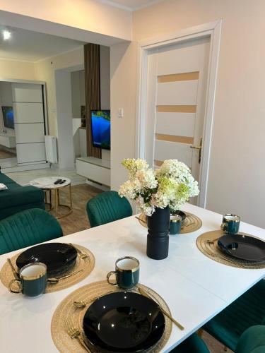 a living room with a table with two plates and flowers at Apartament Gold - Góry Sowie - Głuszyca in Głuszyca