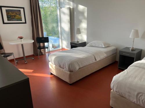 a bedroom with two beds and a table and a window at Hótel Bifröst in Bifrost