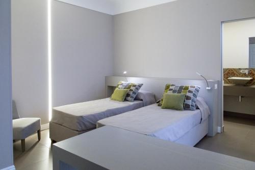 a hotel room with two beds and a chair at Viacolvento in Marsala