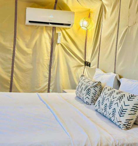 a bed in a tent with two pillows on it at Berber Camp in Merzouga