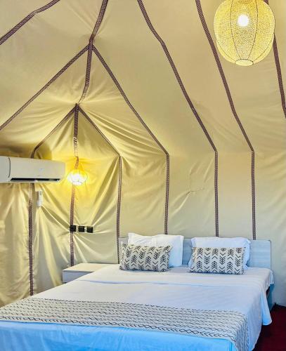 a bed in a tent with two pillows on it at Berber Camp in Merzouga
