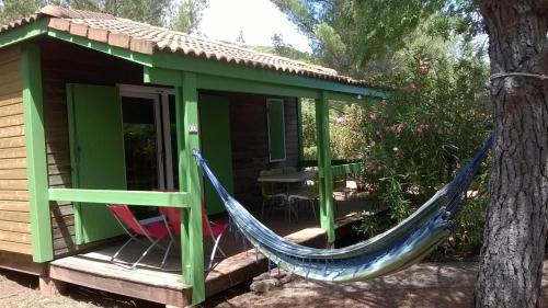 a hammock on the porch of a house at Relais du Salagou - Chalets climatisés proche Lac du Salagou in Le Bosc