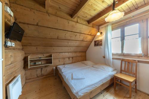 a small bedroom with a bed and a chair at Polana Sosny in Niedzica Zamek
