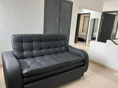 a black leather couch sitting in a living room at Tu casa en Ipiales in Ipiales