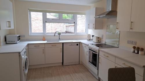 a kitchen with white cabinets and a sink and a window at 3 Bed House Sleeps 6 In Calne in Calne