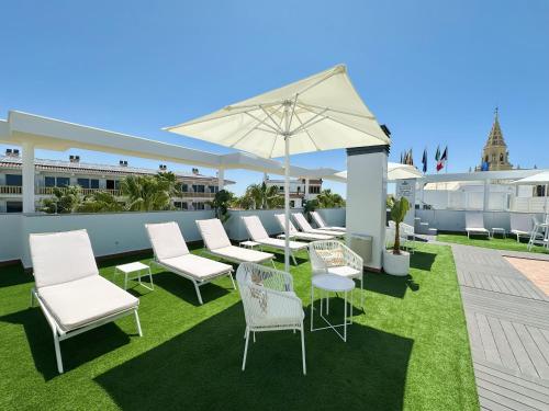a group of chairs and an umbrella on a patio at Hotel Apartamentos Marina Luz in Chipiona