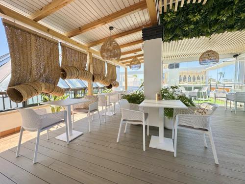 a restaurant with white tables and chairs and windows at Hotel Apartamentos Marina Luz in Chipiona