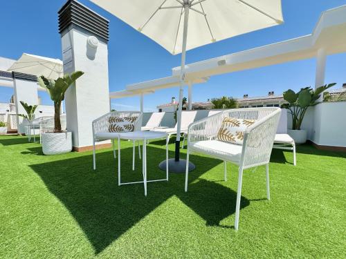 a patio with two white chairs and an umbrella at Hotel Apartamentos Marina Luz in Chipiona