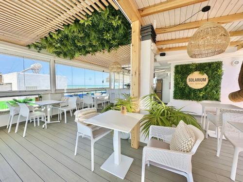 a restaurant with white tables and chairs on a deck at Hotel Apartamentos Marina Luz in Chipiona