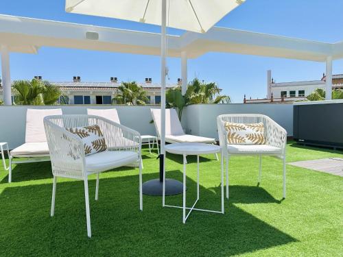 two chairs and a table under an umbrella on a patio at Hotel Apartamentos Marina Luz in Chipiona
