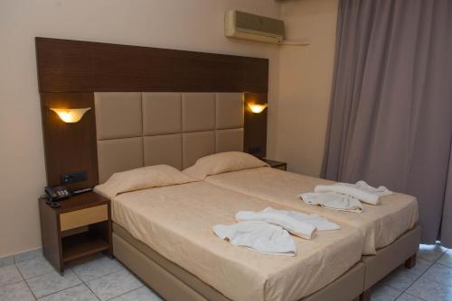 a bedroom with a bed with towels on it at Alexander The Great Hotel in Laganas