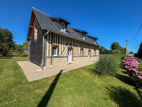 Saint-DésirにあるMaison normande à la campagneの前に芝生の庭がある古い納屋