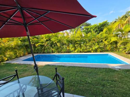 a red umbrella sitting next to a swimming pool at Beautiful home in El Tigre golf course Nuevo Vallarta! in Nuevo Vallarta 