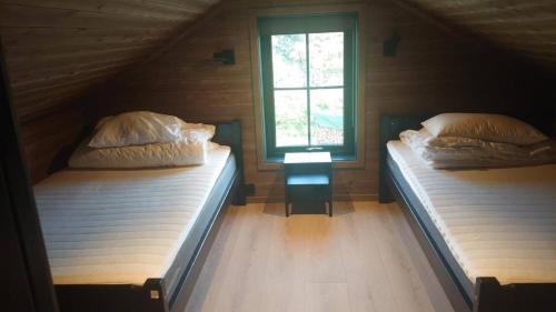 two beds in a room with a window at 2 cabins surrounded by beautiful nature in Stryn