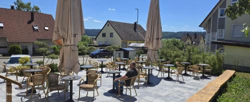 a woman sitting at a table with chairs and umbrellas at Hotel Krone UG in Deißlingen