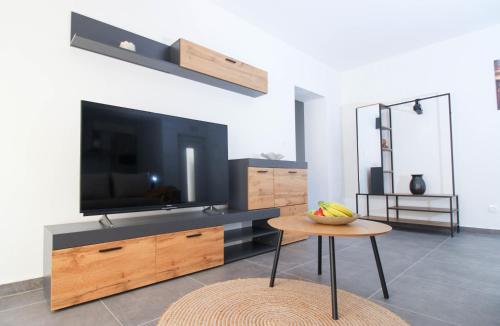 Una sala de estar con un televisor y una mesa. en Fly in Apartment, en Čilipi