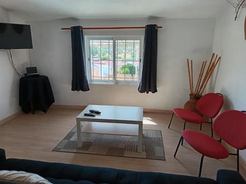 a living room with a table and two red chairs at Casa Calhameiro in Redondo