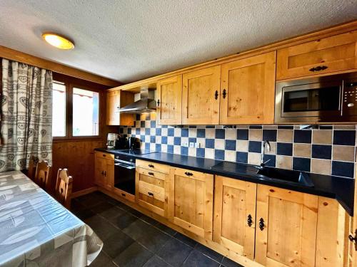 une cuisine avec des armoires en bois et un comptoir noir dans l'établissement Résidence Courmayeur - Bel appartement rénové pour 6-8 personnes sur les pistes MAE-4094, aux Menuires