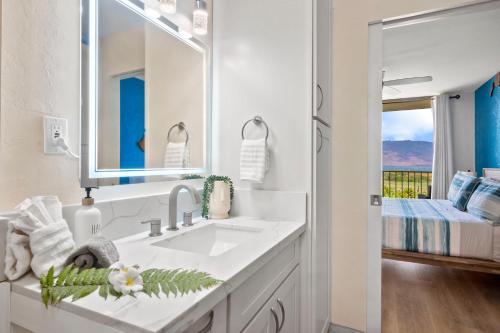 Un baño blanco con lavabo y espejo. en Sunset Palms Kihei s Cozy Beach Escape, en Kihei