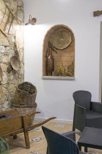 a clock on a shelf in a room with chairs at Dimora S'Ena Manna in Oliena