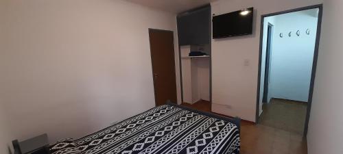 a bedroom with a bed with a black and white blanket at Hospedaje Alicia in Barraquero