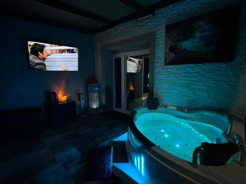a dark bathroom with a tub and a tv at Apartament Queen in Ełk