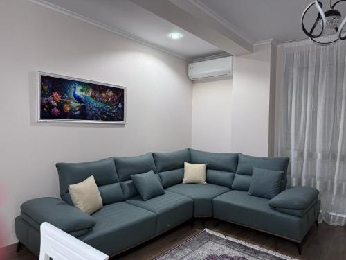 a living room with a blue couch and a painting at Anika's Place in Korçë