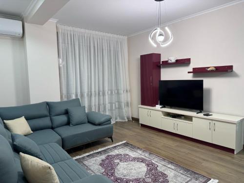 a living room with a blue couch and a tv at Anika's Place in Korçë